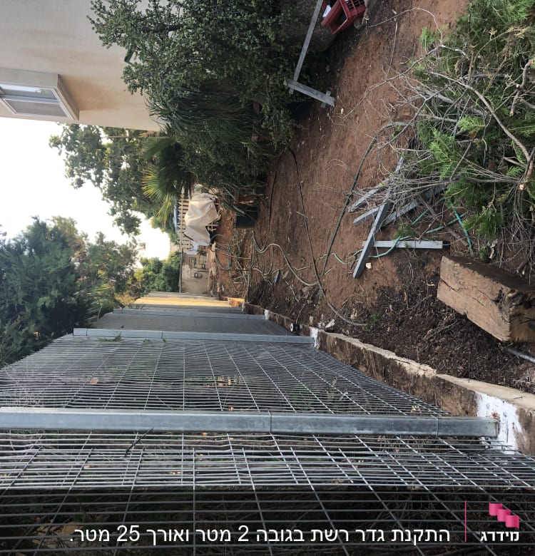 מסגרת מתכתית גדולה מונחת על הקרקע ליד שיחים